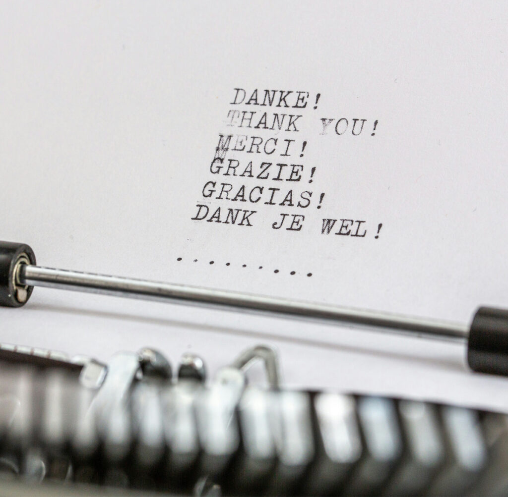 Image of a typewriter (barely seen in image), with the words Danke!, Thank you!, Merci!, Grazie!, Gracias! and Dank Je Wel! Photo by Wilhelm Gunkel on Unsplash.